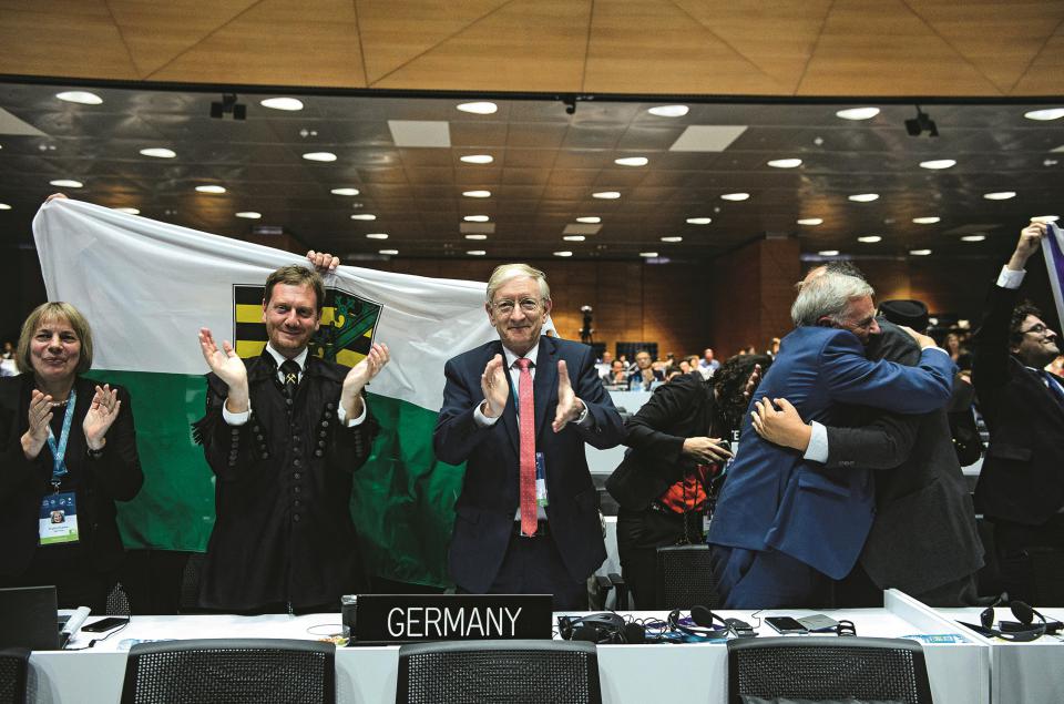 Michael Kretschmer und UNESCO-Botschafter Stefan Krawielicki jubeln in Baku, hinter ihnen wird die Sachsen-Flagge geschwenkt