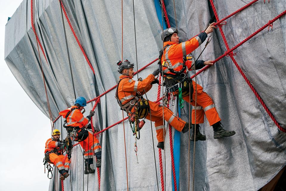 Professional climbers from Compagnie des Guides de Chamonix link the ropes to steel rope connectors, which are attached through “button holes” in the fabric to the steel structure