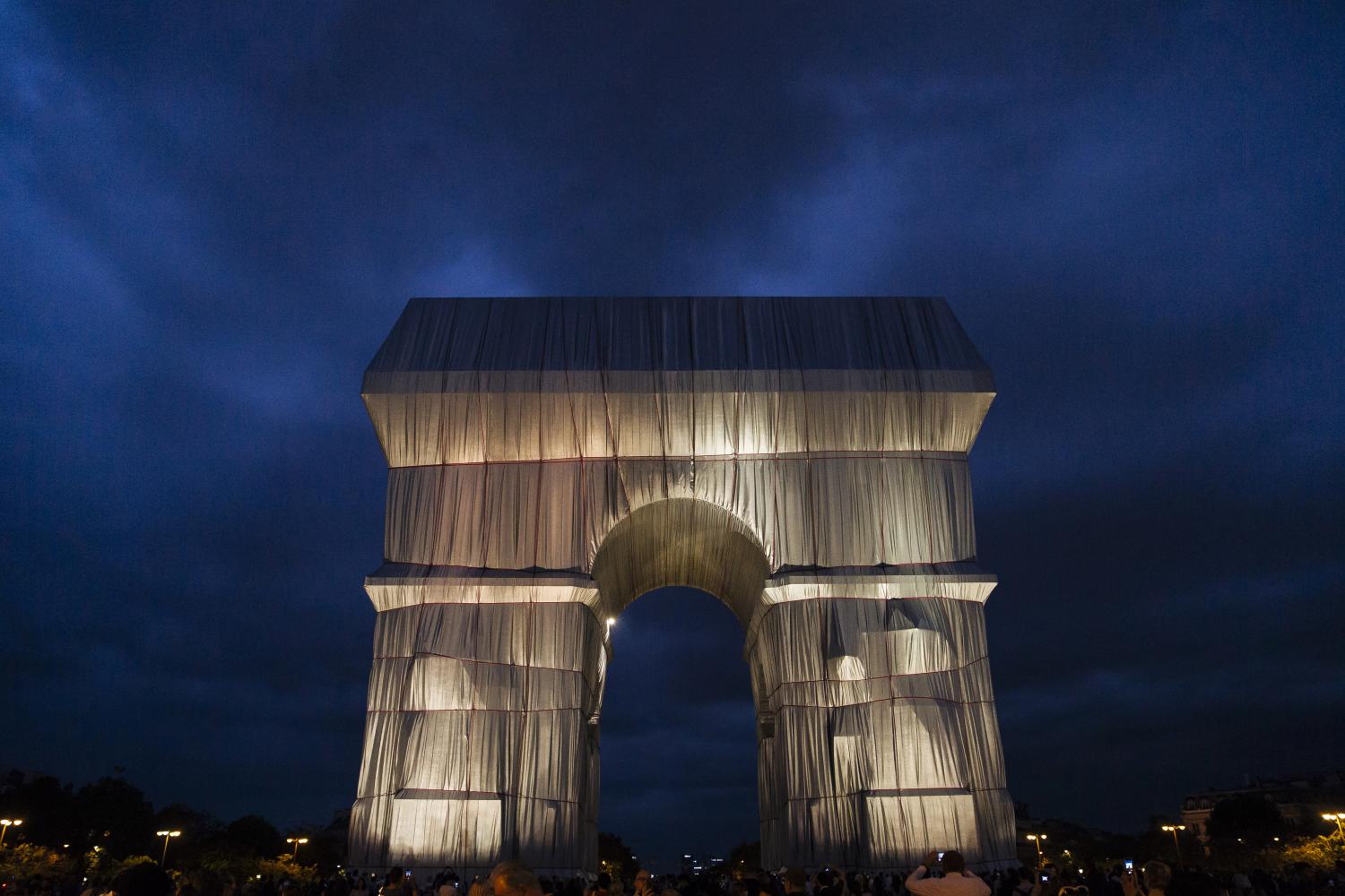 Eine Nachtaufnahme zeigt den Arc de Triomphe in Paris, der nach dem Entwurf des verstorbenen Künstlerpaars Christo und Jeanne-Claude in silberblauen Stoff gehüllt wurde